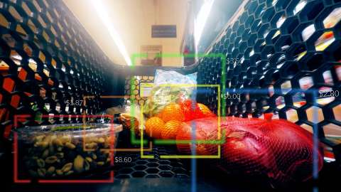 さまざまな食品アイテムが入ったスーパーのショッピング・カートの中のクローズアップ画像。各アイテムの周囲には、コンピューター・ビジョンによる認識枠を表す色のついた輪郭が表示されている。